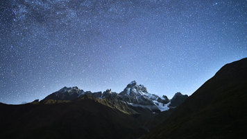 Lege dich unter dem Sternenhimmel, weit von der Zivilisation, hin! Träume groß und beseelt mit dem Hintergrundbild Gebirge-Sterne.